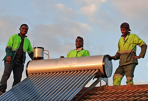 3 men standing on rooftop after solar geyser installations in Zimbabwe