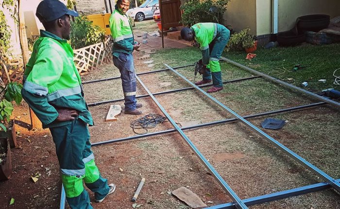 Men drilling, grinding and welding, building solar panels stand for rooftop